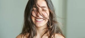 Smiling woman with windswept hair showing a bright, natural smile
