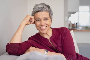 Smiling woman with short grey hair relaxing on a sofa