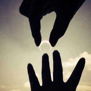 Silhouetted hands reaching toward each other against a glowing sky