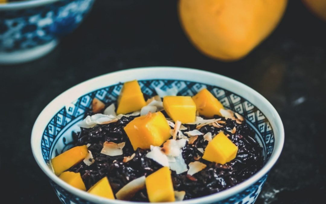 Bowl of dark chia pudding topped with mango and coconut