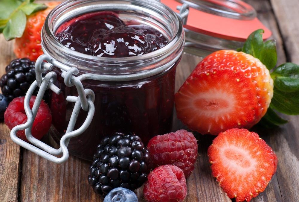 Jar of homemade berry jam with fresh strawberries, blackberries and raspberries