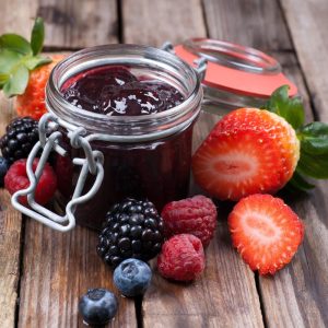 Jar of homemade berry jam with fresh strawberries, blackberries and raspberries