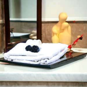 Yellow sculpted magnesium soap figure beside folded white towels on a black tray