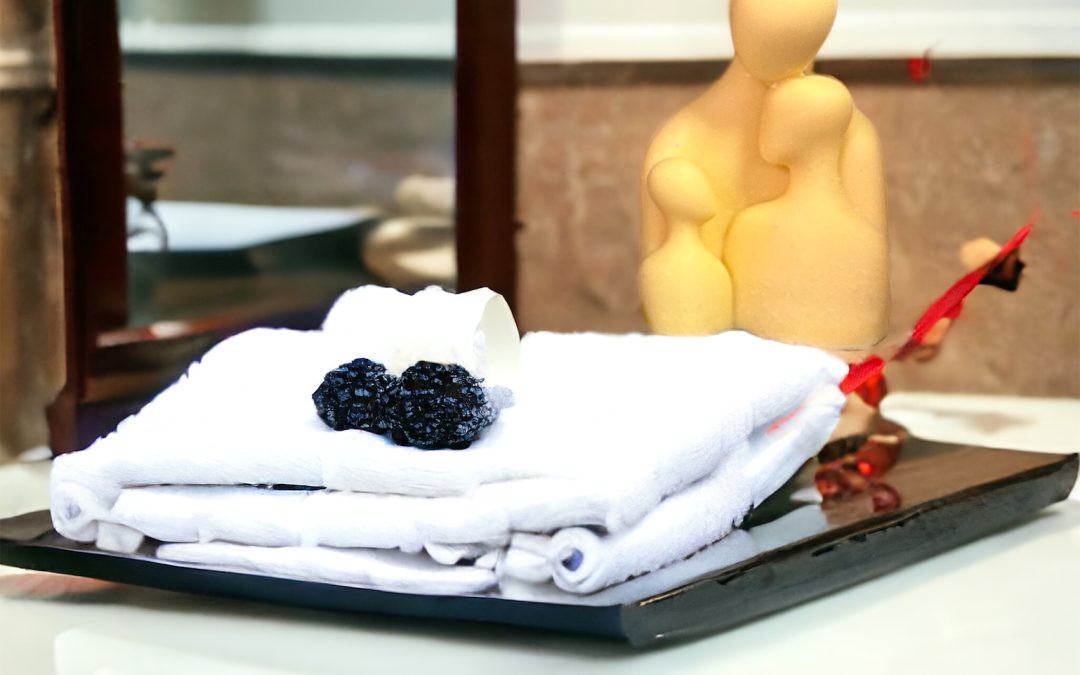 Yellow sculpted magnesium soap figure beside folded white towels on a black tray