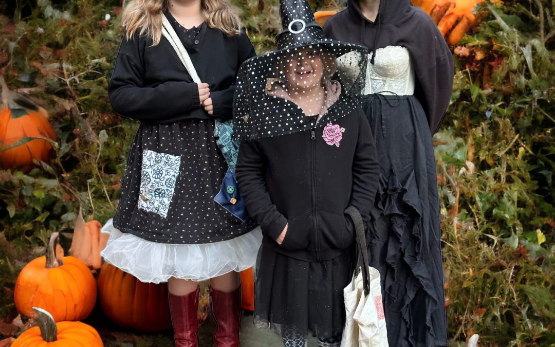 Family in Halloween costumes among pumpkins in the garden