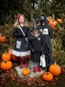 Family in Halloween costumes among pumpkins in the garden