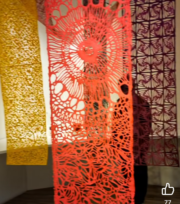 Red and yellow cut-paper art installation hanging in a gallery
